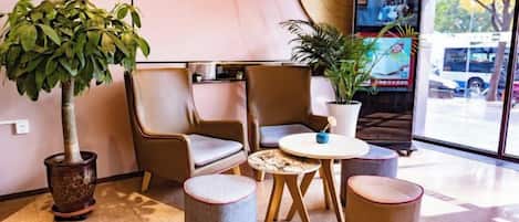 A seating area with chairs and a small table, a potted plant, and a television screen.