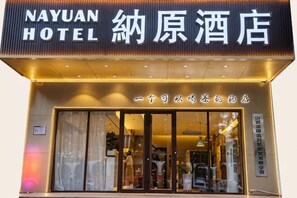 L’entrée d’un hôtel, avec une enseigne indiquant « HÔTEL NAYUAN » et une grande porte en verre.