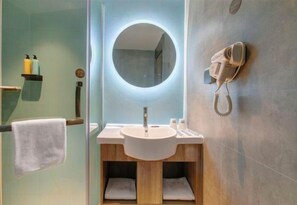 A modern bathroom with a round mirror, a hairdryer, and a sink.