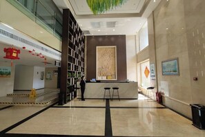 A hotel lobby with a reception desk, a large bookshelf, and a modern interior design. - Zhengzhou Yindu Hotel (China Great Wall Aluminum) (Zhengzhou)