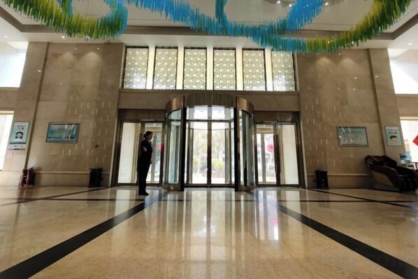 A lobby with a revolving door, a reception desk, and a large window with a view.
