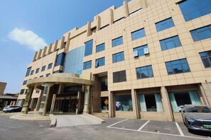 A multi-story hotel with a modern design, featuring a central entrance with a curved structure, large windows, and a parking area in front. - Zhengzhou Yindu Hotel (China Great Wall Aluminum) (Zhengzhou)