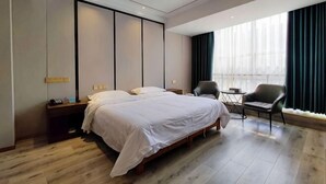 A modern hotel room with a large bed, a desk, a chair, and a view of the city through large windows. - Zhengzhou Yindu Hotel (China Great Wall Aluminum) (Zhengzhou)