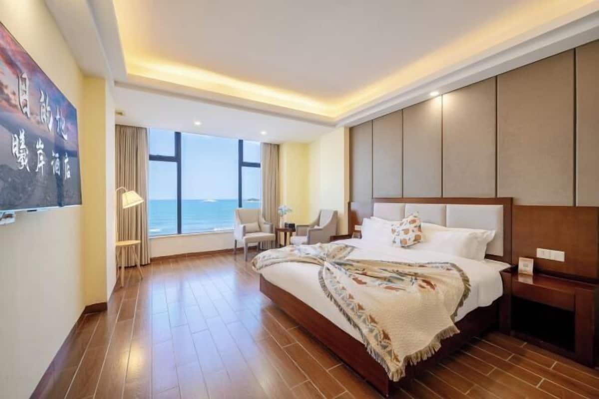 A hotel room with a large bed, a view of the sea, and a modern design.