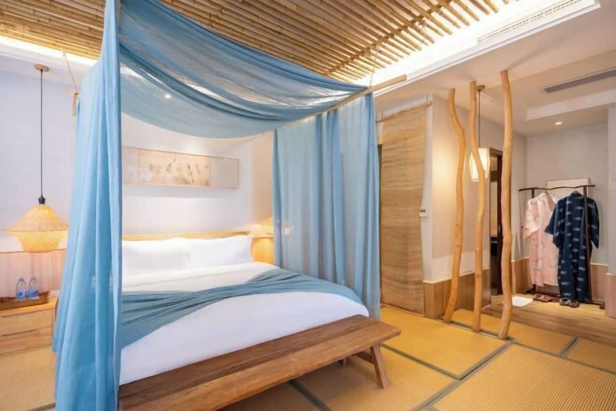A modern bedroom with a bed, a bedside table, a hanging lamp, and a wardrobe.