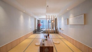 A hallway with tatami mats, a wooden table, and a view of the sea. - Destination Xi An Hotel (Huidong)