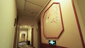 En hotelgang med et stort vægmaleri, et skilt med pile og et mønstret tæppe.