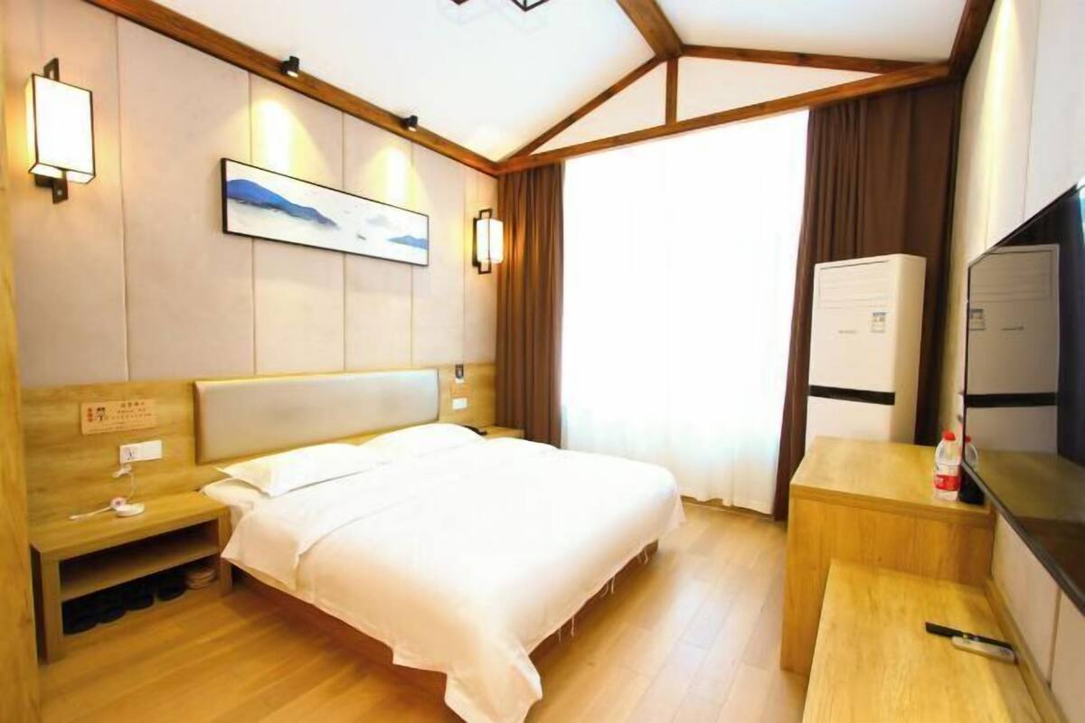 Una habitación de hotel con cama, mesita de noche, lámpara, obra de arte y televisor.