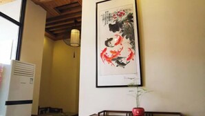 Un área de comedor con una mesa, sillas, un jarrón rojo y una obra de arte enmarcada en la pared.