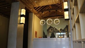 Et receptionsområde med træloft, en receptionsdisk og runde lysarmaturer på væggen.