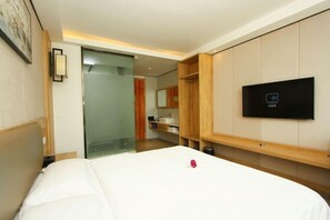 A hotel room with a bed, a television mounted on the wall, and a sliding door leading to a bathroom. - Jinhui Fashion Hotel (Baicheng)