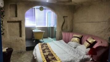 Quarto com cama, cabeceira rosa e janela com persianas.