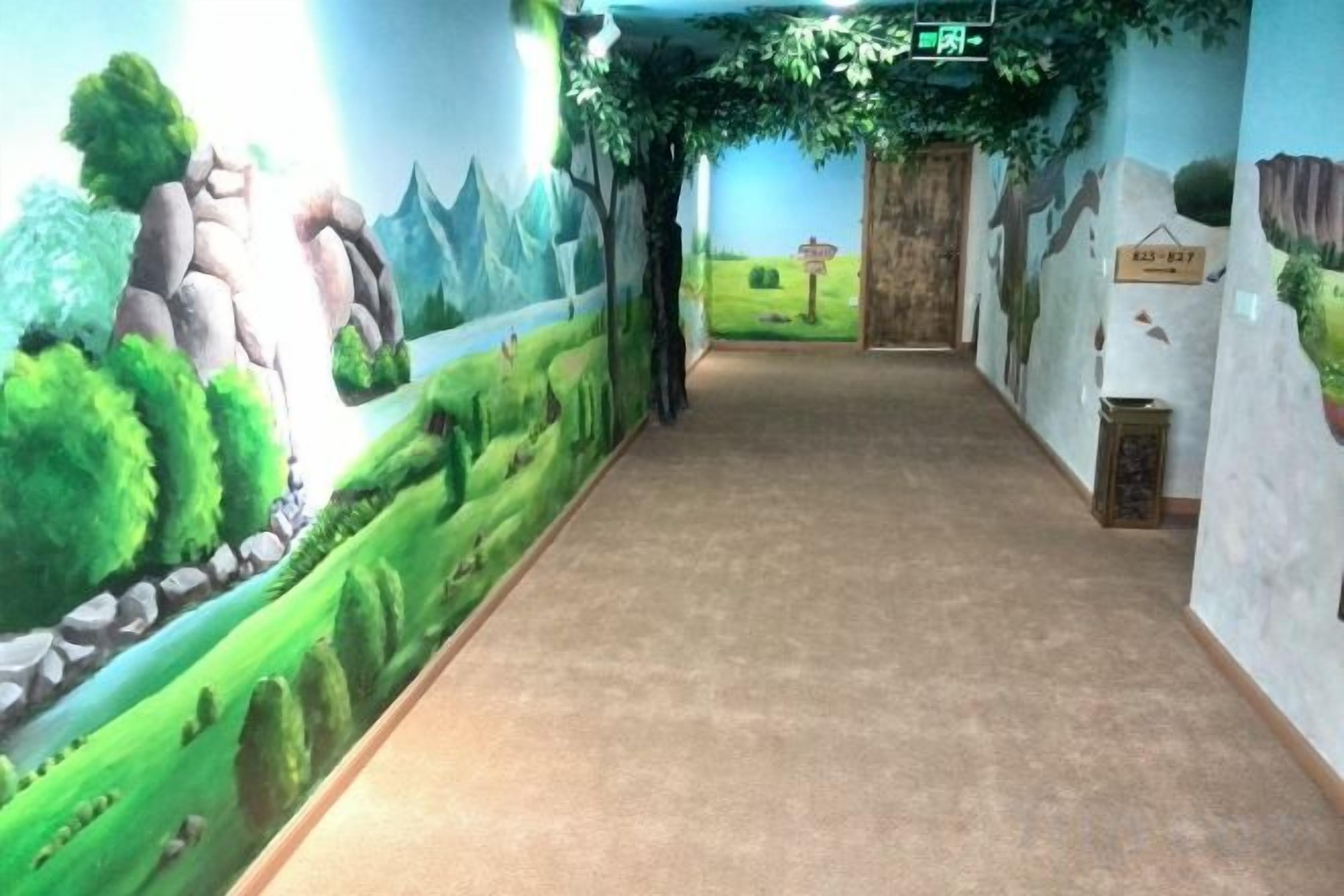 A hallway with a mural of a landscape, a carpeted floor, and a wooden door at the end.
