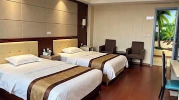 Quarto de hotel com duas camas, uma escrivaninha, uma cadeira e vista para palmeiras.