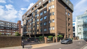 A multi-story residential building with a brick facade, multiple windows, and a gated entrance.