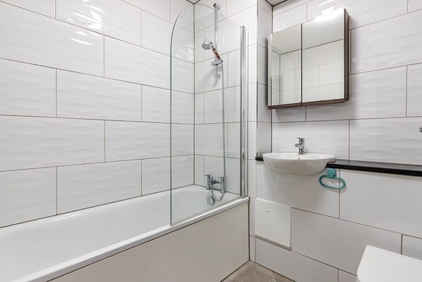 A modern bathroom with a glass-enclosed shower, a white sink, and a mirror above the sink.