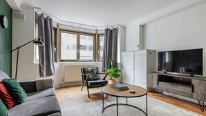 A modern living room with a sofa, a round coffee table, a television, and a radiator.