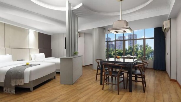 A modern hotel room with a large bed, a dining area, and a view of the cityscape. - Hyatt Regency Loudilai (Loudi)