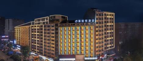 A multi-story hotel with a modern design, featuring a prominent entrance and a parking area in front.