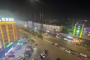A multi-story building with illuminated signage, a parking lot with several cars, and a busy street with traffic. - Hyatt Regency Loudilai (Loudi)