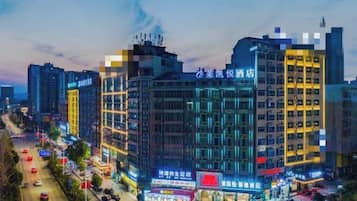 A multi-story hotel with illuminated signage, a busy street in the foreground, and other buildings in the background.