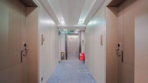 A hotel corridor with a blue carpet, wooden doors, and a visible elevator. - Hyatt Regency Loudilai (Loudi)