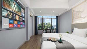 A hotel room with a large bed, a wall-mounted TV, a dining table with chairs, and a view of the city through large windows. - Hyatt Regency Loudilai (Loudi)