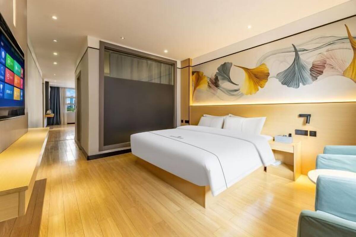 A modern hotel room with a large bed, a desk, and a TV.