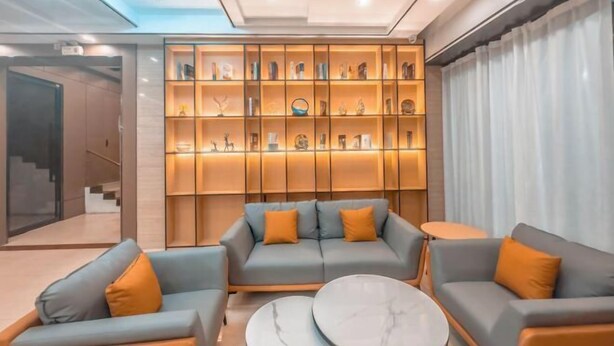 Una sala de estar moderna con un sofá, una mesa de centro y una pared de estanterías con objetos decorativos.