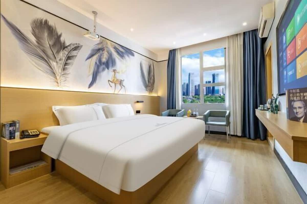 A hotel room with a large bed, a desk, and a view of the city.