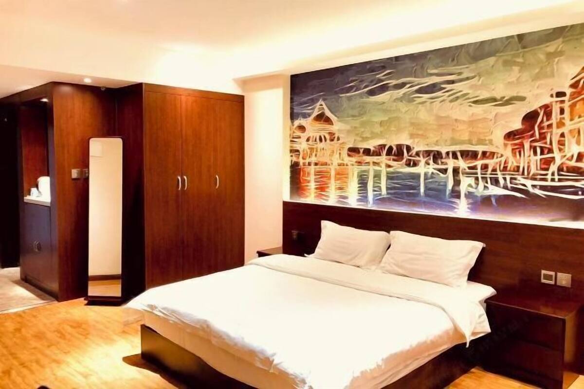 Una habitación de hotel con cama, armario de madera y un cuadro en la pared.
