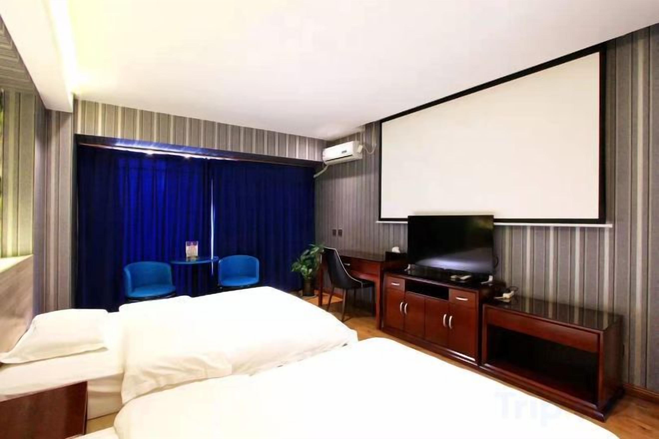 A hotel room with a bed, a desk, a television, and a seating area with chairs.