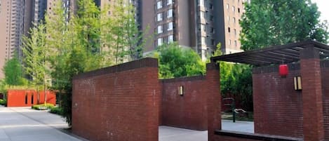 A gated entrance to a residential building with a brick wall and a covered walkway.