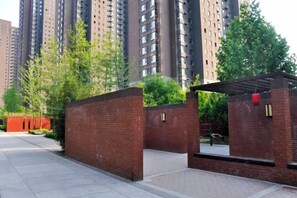 A gated entrance to a residential building with a brick wall and a covered walkway. - Taiyuan Live Service Apartment (Taiyuan)
