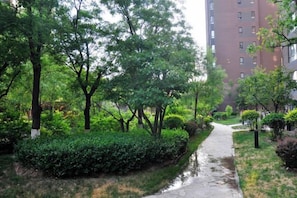 A pathway flanked by lush greenery and a tall building in the background. - Taiyuan Live Service Apartment (Taiyuan)