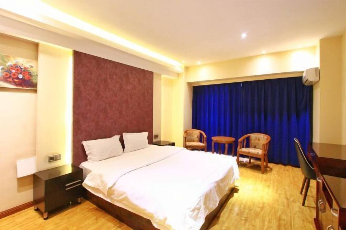Una habitación de hotel con cama, dos sillas, un escritorio y una cortina azul.