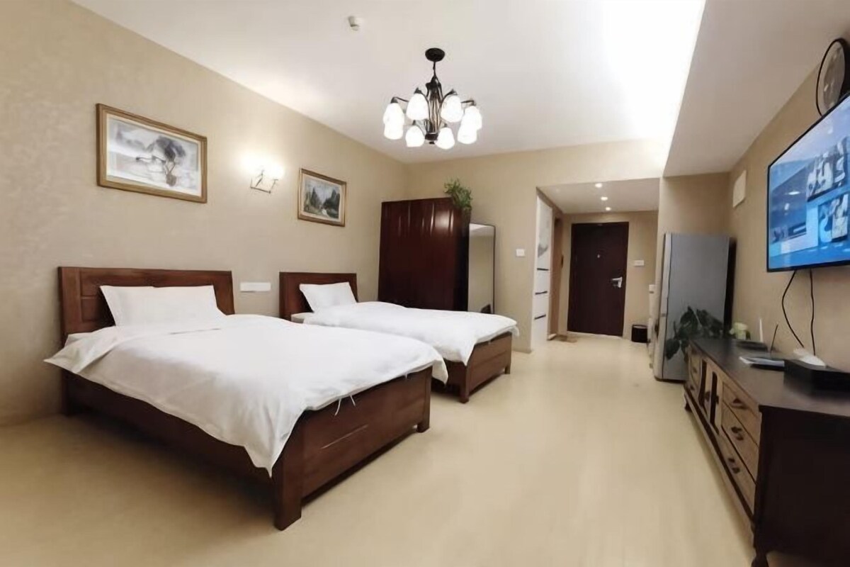 A hotel room with two beds, a television, and a desk.