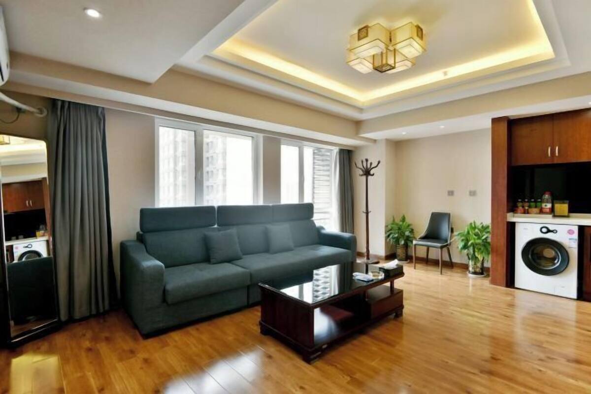 Una sala moderna con un sofá modular, una mesa de centro, una zona de comedor con una silla y una lavadora.