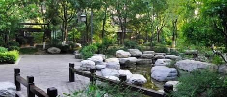 A wooden bridge over a pond with rocks and greenery.