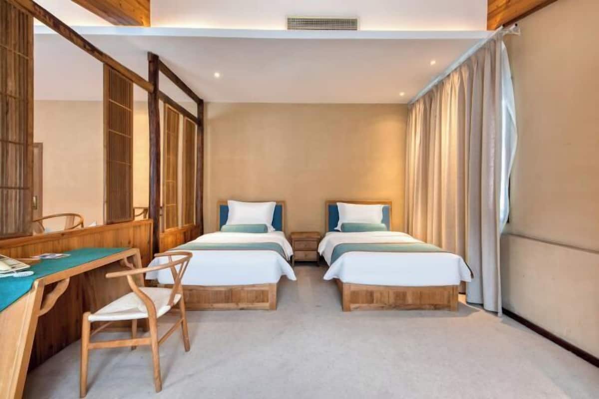 Habitación de hotel con dos camas, un escritorio y una silla.