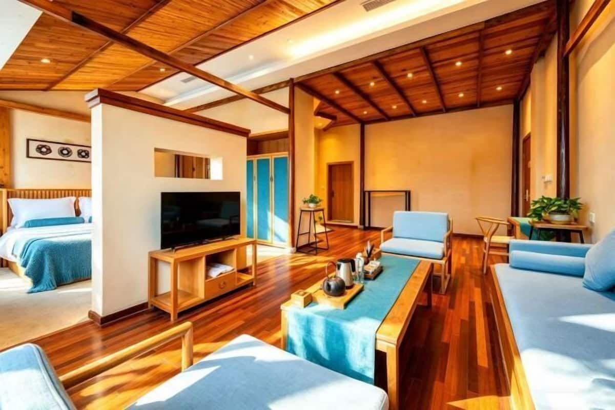 Una sala de estar moderna con techo de madera, televisor, sofá y comedor.