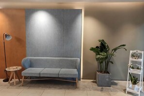 A modern interior with a sofa, a floor lamp, a potted plant, and a white shelving unit. - Homeinn · neo (Chengdu Chunxi Road Taikoo Li Store) (Chengdu)