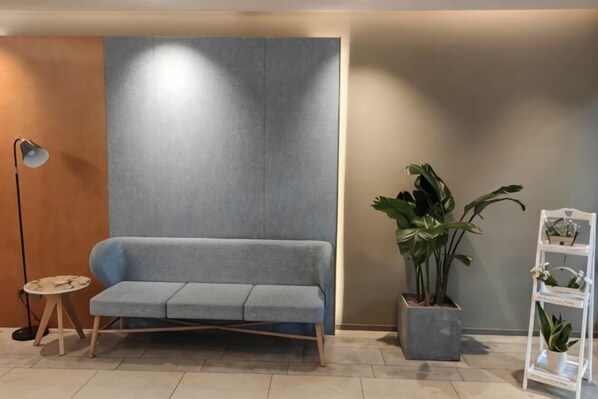 A modern living area with a grey sofa, a floor lamp, a potted plant, and a white shelving unit. - Homeinn · neo (Chengdu Chunxi Road Taikoo Li Store) (Chengdu)