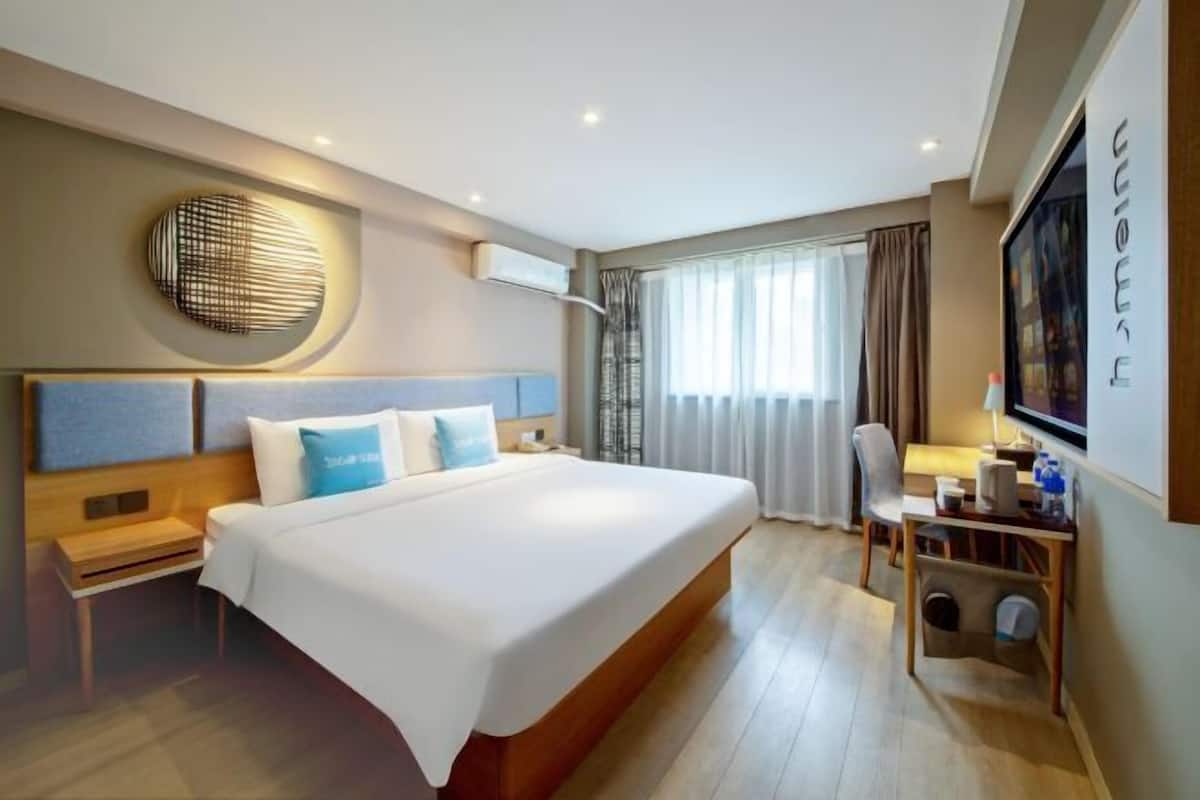 A modern hotel room with a large bed, a desk, and a television.