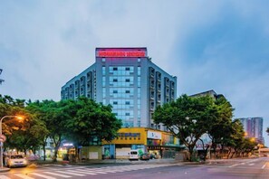 A multi-story hotel with a prominent sign at the top, surrounded by trees and a crosswalk. - Homeinn · neo (Chengdu Chunxi Road Taikoo Li Store) (Chengdu)