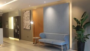 A modern lobby with a light blue sofa, a floor lamp, and a large abstract painting on the wall. - Homeinn · neo (Chengdu Chunxi Road Taikoo Li Store) (Chengdu)
