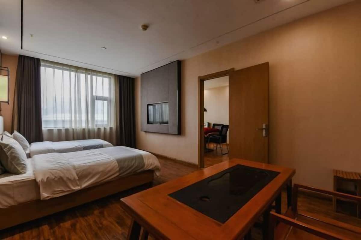 A modern hotel room with a bed, a wooden table, and a TV mounted on the wall.