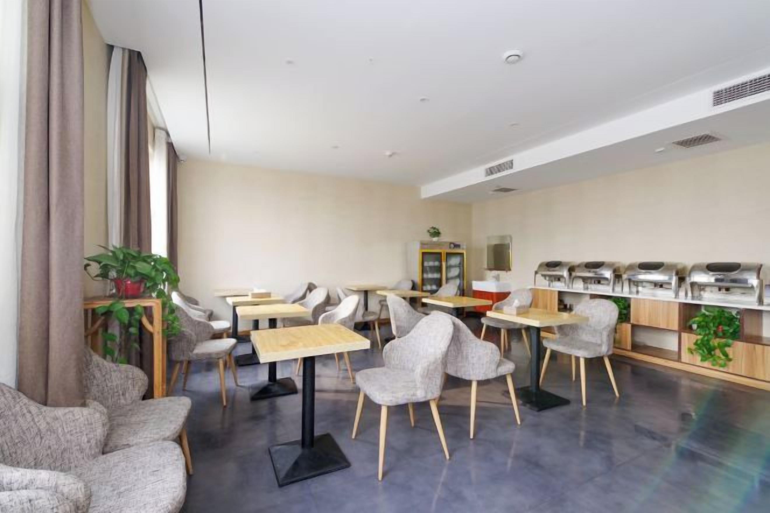 A modern dining area with multiple tables and chairs, a coffee station, and a potted plant.