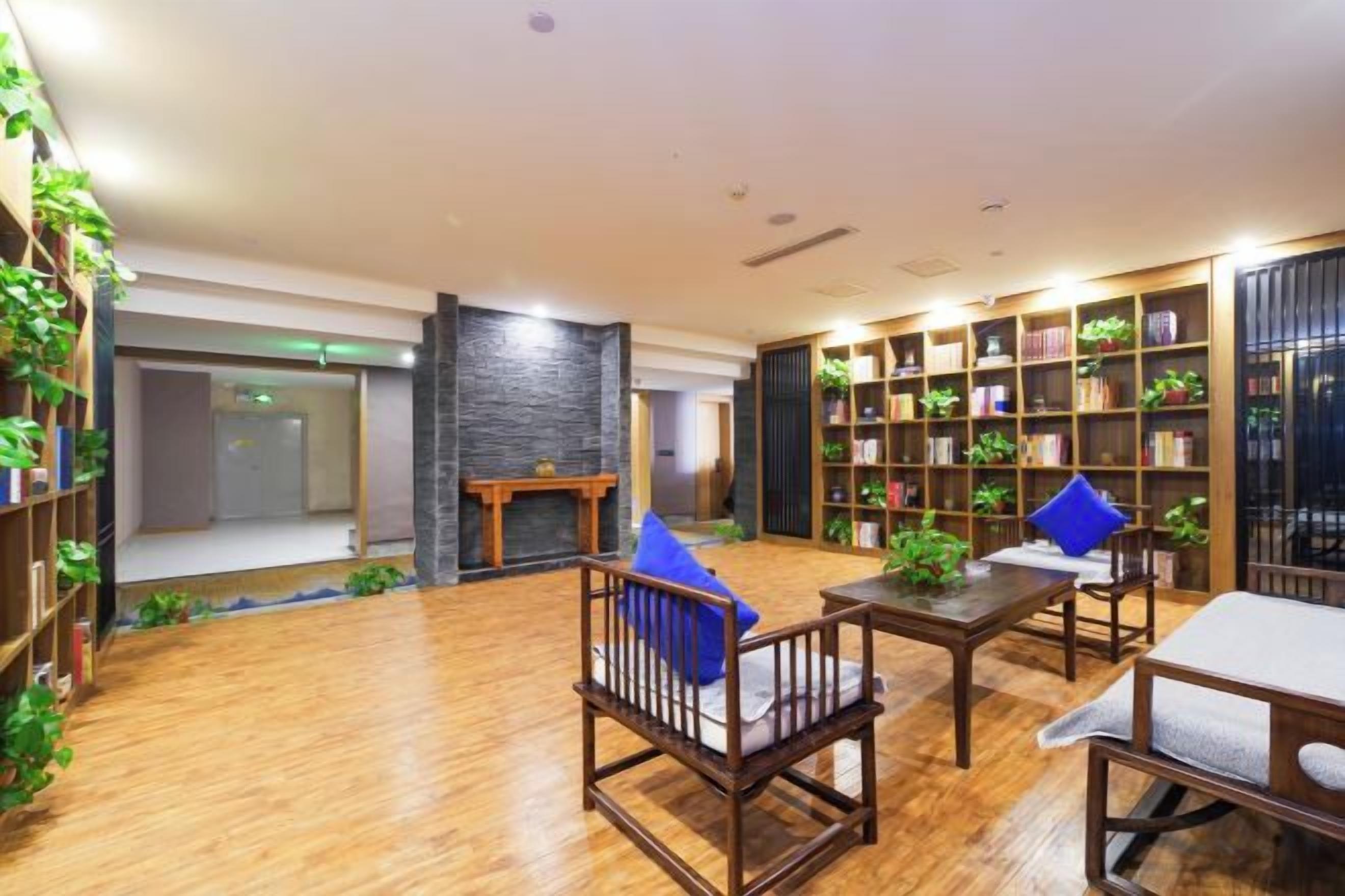A spacious room with a fireplace, wooden flooring, and a bookshelf filled with books and plants.