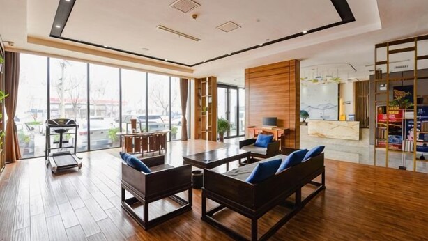 A spacious lobby with a reception desk, seating area, and large windows offering a view of the outside. - Riyue Lake Culture Hotel (Shangqiu)